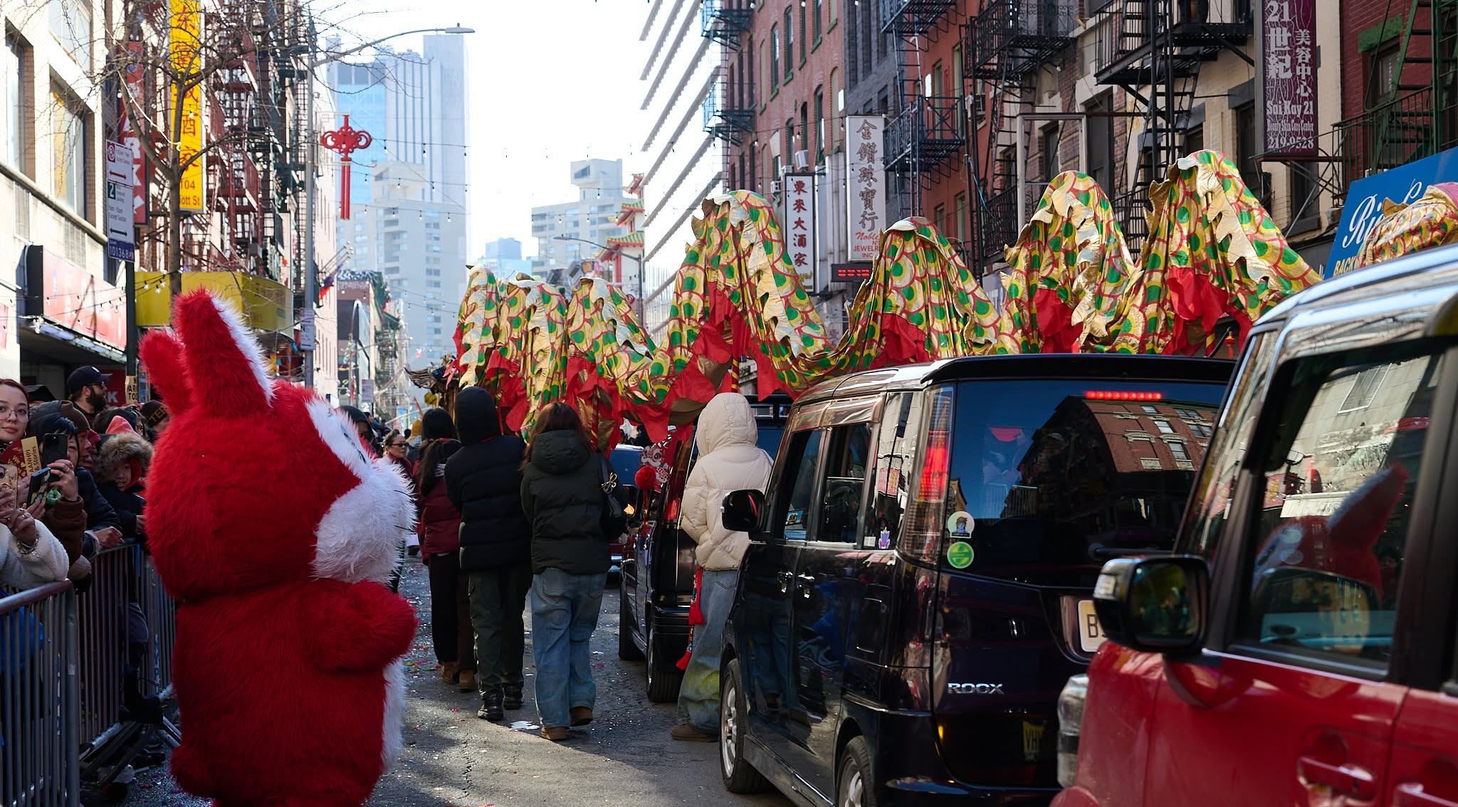 The dragon dance moving down a car-lined Chinatown street